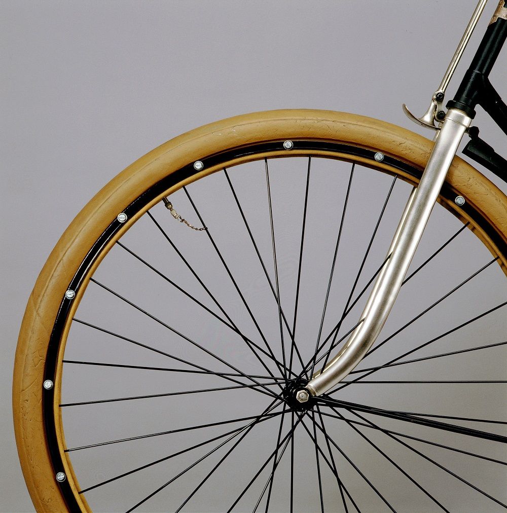 Photographie du premier pneu démontable : de couleur ocre brun, sa surface est lisse. Il présente un système de cerclage qui peut être détaché de la structure pour changer la pièce abîmée.